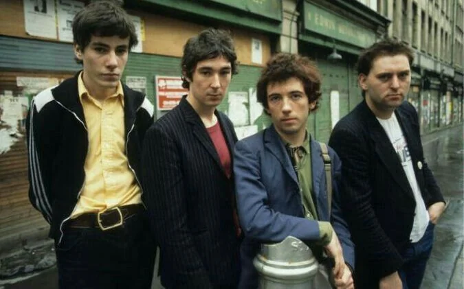Four young men in punk-era clothing photographed on a London street