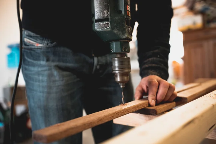 Hands measuring a length of timber at a workbench
