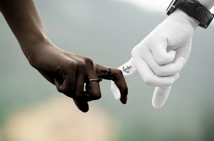 Two hands reaching towards each other in black and white