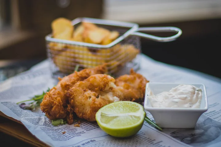 A basket of fried food served with lemon and dip