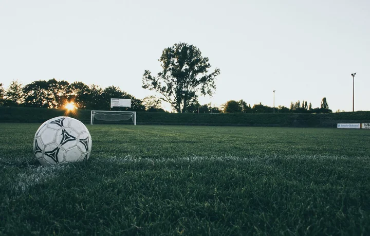 A football resting on a pitch in front of a goal