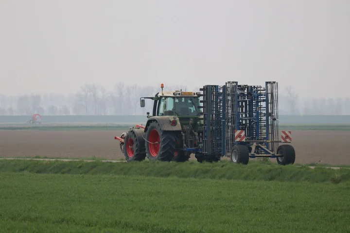 A tractor with a wide implement spraying a field