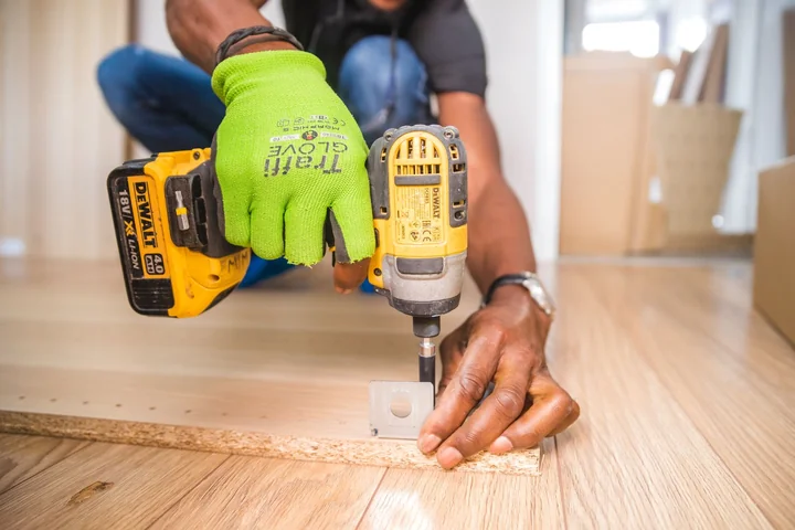 A person drilling into a wooden floor