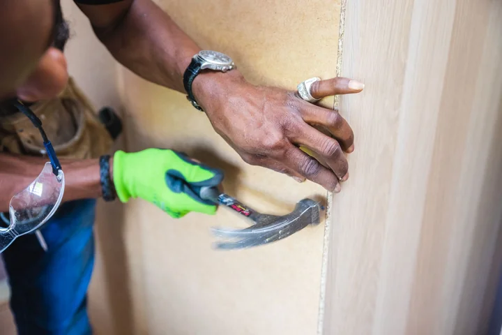 Hands using a chisel on a door frame