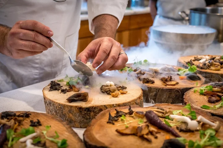A chef plating canapes on wooden boards