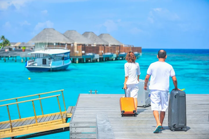 Two people with suitcases on a tropical jetty