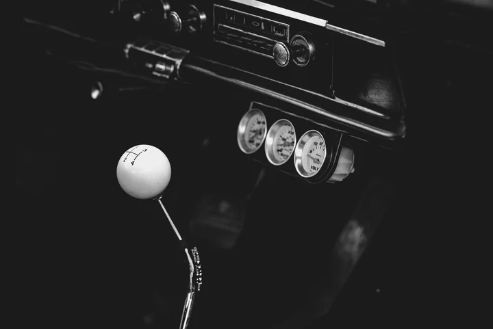 The gear lever and dials of a classic car in black and white