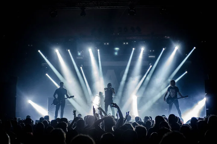 A concert stage lit by beams above a crowd