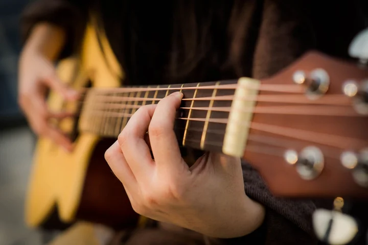 Hands playing an acoustic guitar