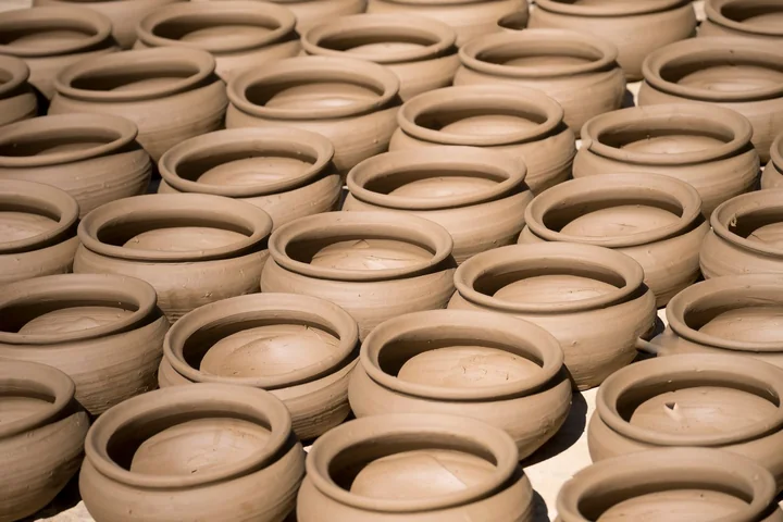 Rows of unfired clay bowls drying in a pottery