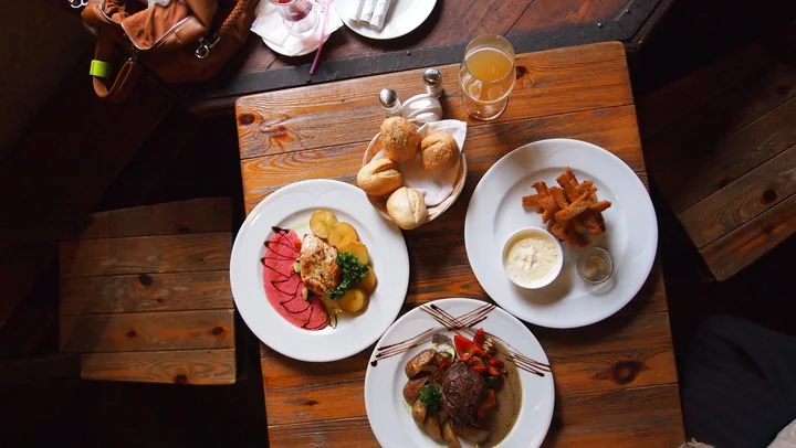 A wooden table set with several breakfast plates