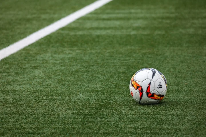 A football sitting on the line of a grass pitch