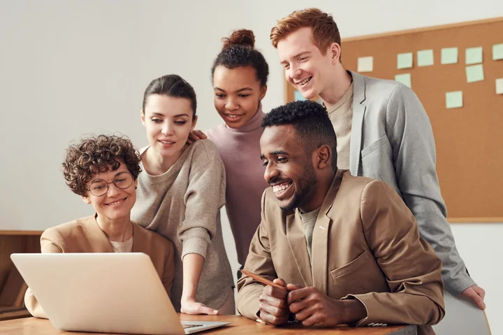 A team gathered around a laptop, smiling