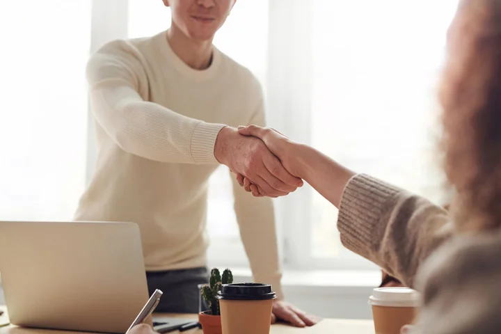 Two people shaking hands across a desk