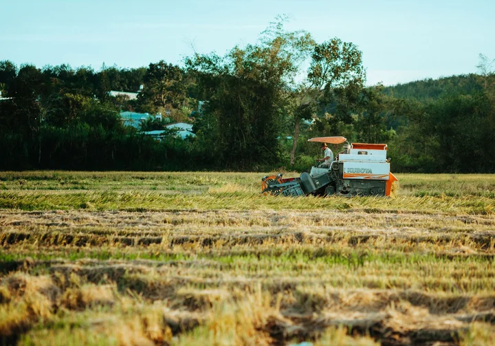 A harvester cutting a field with hills behind