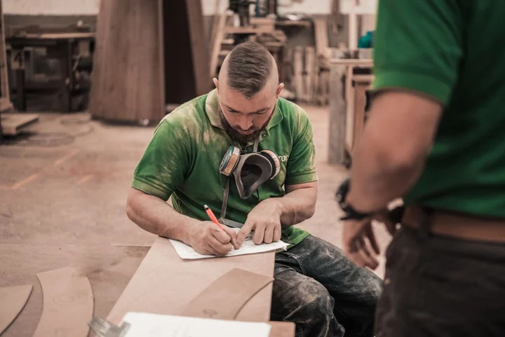 A man writing notes at a workbench