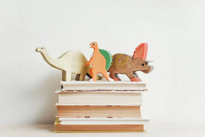 Small toy dinosaurs standing on a stack of books