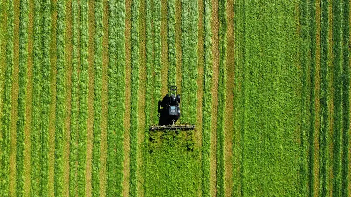 An aerial view of a tractor on a striped green field