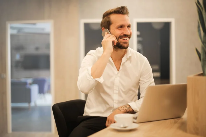 A man on the phone at a laptop in an office