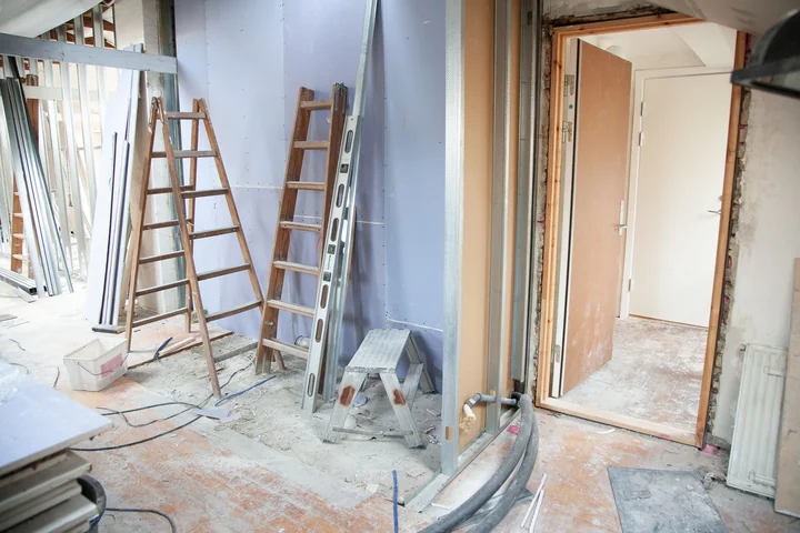A room mid-renovation with bare walls and a ladder