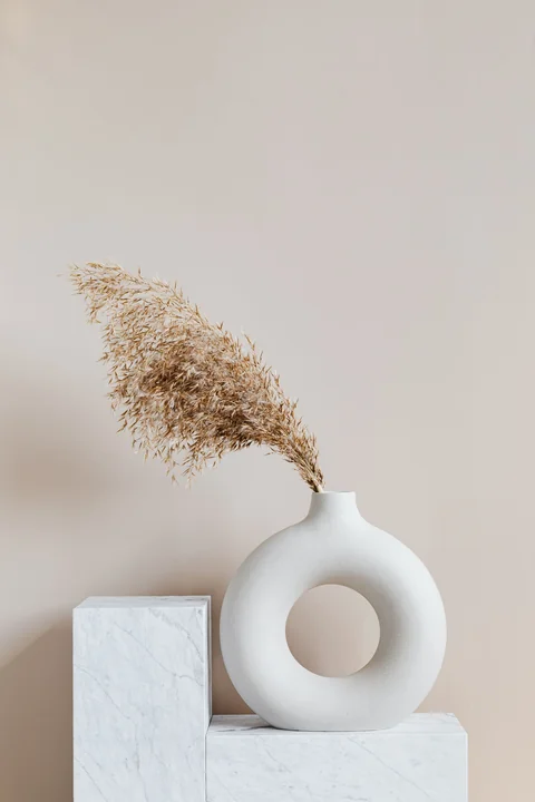 A white ceramic vase holding dried grasses