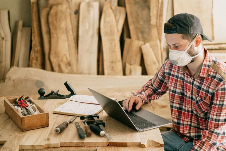 A woodworker in a dust mask working at a bench