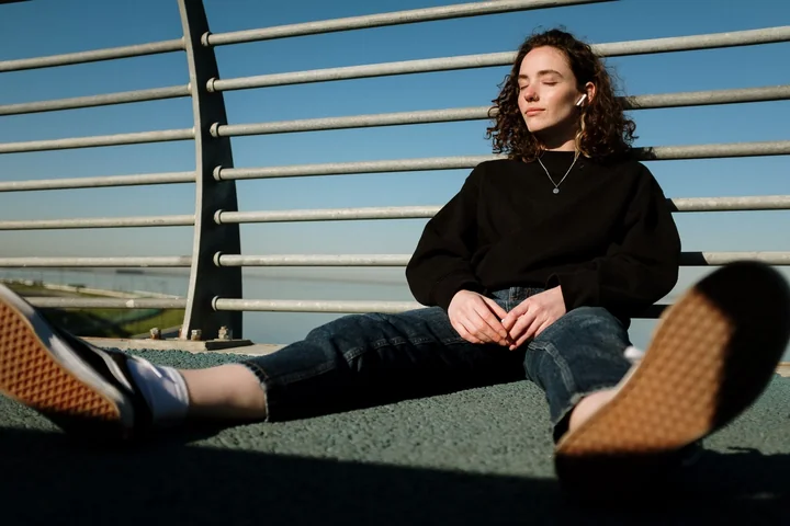 A young woman sitting on a walkway outdoors