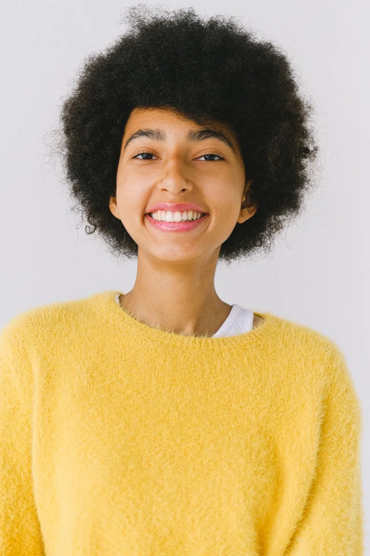 A woman in a yellow jumper against a plain background