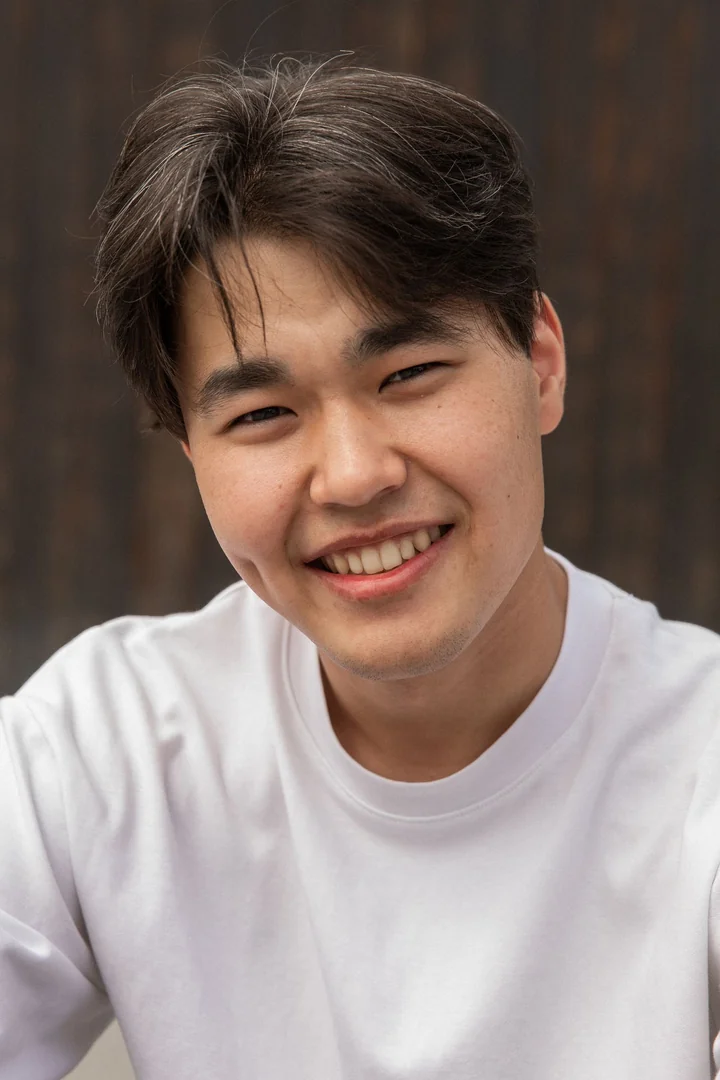 A young man smiling against a plain background