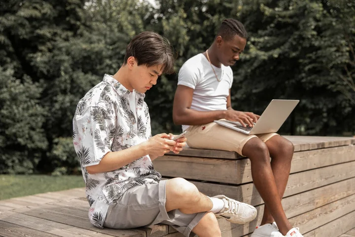Two people sitting outdoors working on a laptop