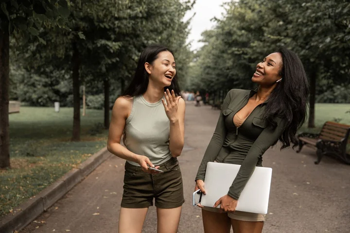 Two friends walking and talking along a tree-lined path