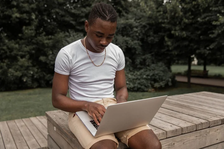 A man working on a laptop on an outdoor bench