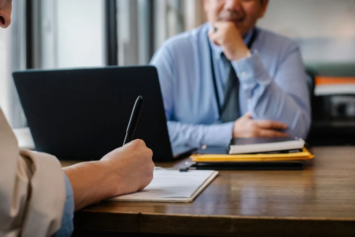 Two people signing paperwork at a desk