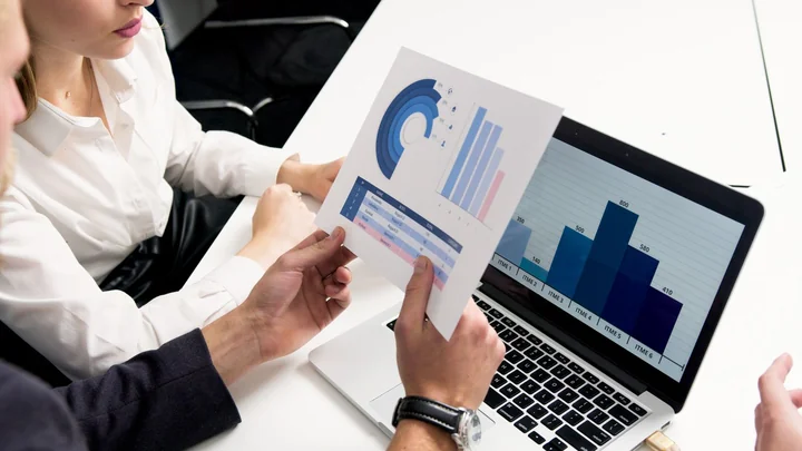 Hands holding a printed chart beside a laptop