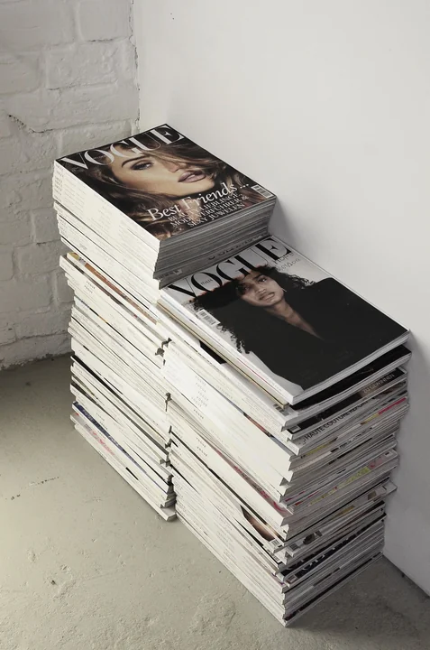 A stack of magazines against a plain wall