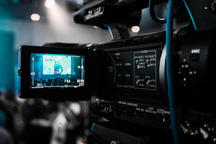 A professional video camera with its monitor open