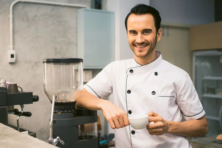 A chef in whites smiling in a professional kitchen
