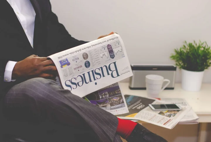 A person reading a business newspaper at a desk